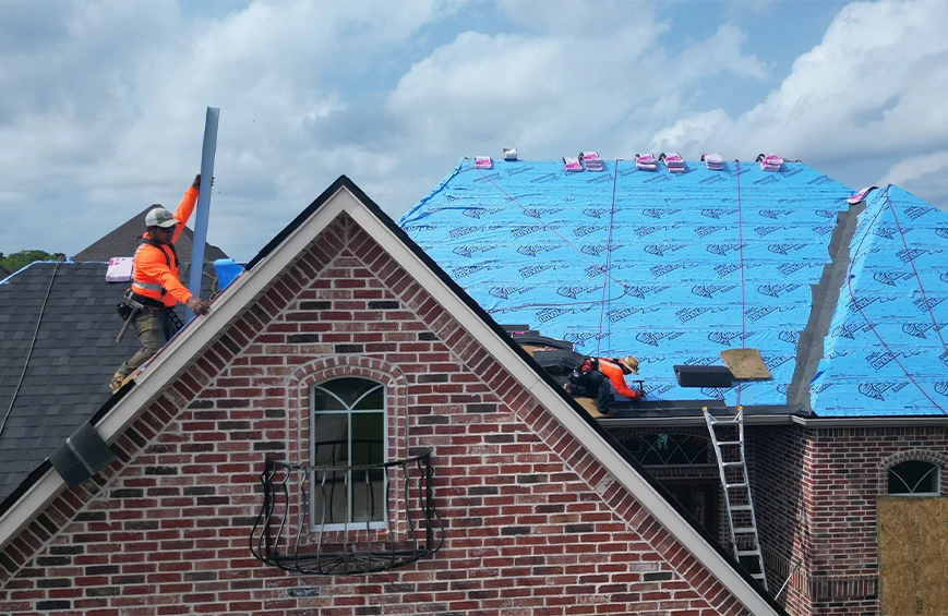 Professional roofing contractors installing a new residential roofing system on a brick home.